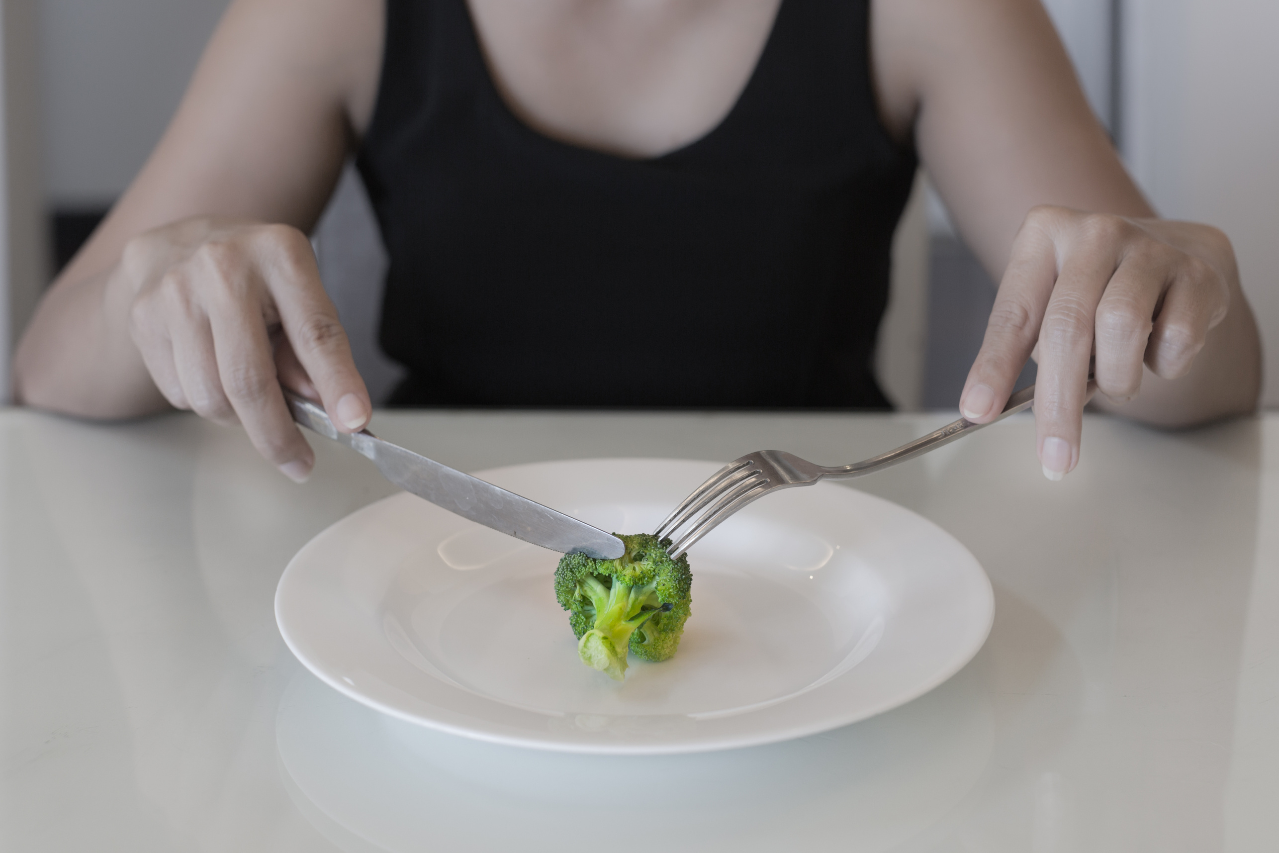 A hungry woman on a weight loss diet. Empty plate with a vegetable. Low calorie diet.